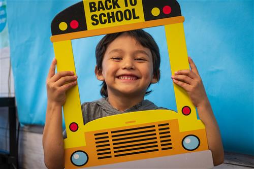Student holds up a bus photo that says back to school. Student holds up a bus photo that says back to school.